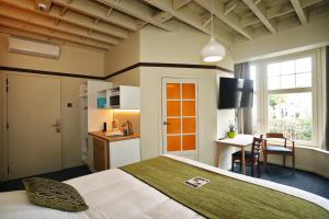 a bedroom with a bed and a desk and a kitchen at Aparthotel Acacia in Eeklo