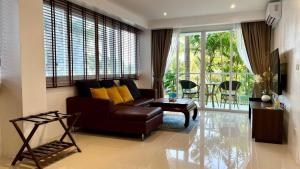 a living room with a brown couch and yellow pillows at Sunset Plaza Condominium in Ban Karon