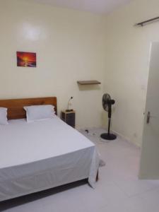 a bedroom with a white bed and a fan at Accueil 1 in Rufisque