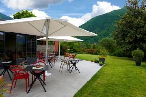 a patio with tables and chairs and an umbrella at Boutique Hotel Villa Cuserina wellness in Cannobio