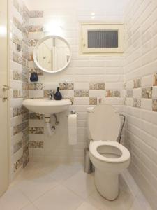 a white bathroom with a toilet and a sink at Holiday apartment Sombrero in Nea Peramos