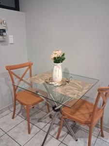 een glazen tafel met een vaas met bloemen en twee stoelen bij TripleM comfort zone in Windhoek