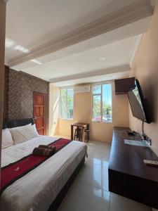 Un dormitorio con una cama, un escritorio y un televisor. en Tomato Motel, en Pantai Cenang