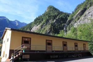 a building with mountains in the background at Agriturismo Mattei - Dormitorio in Peccia