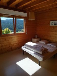 ein Schlafzimmer mit einem Bett in einem Holzzimmer mit einem Fenster in der Unterkunft Grand Valtin : chalet écolo 4 étoiles 14 personnes in Ban-sur-Meurthe-Clefcy