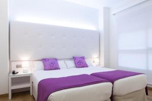 a bedroom with a large white bed with purple pillows at Hotel Albahia Alicante in Alicante