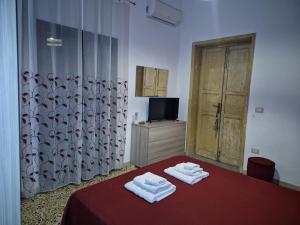 a bedroom with two towels on a bed with a television at NA ZA ROSA - Casa Vacanze in Porto Empedocle