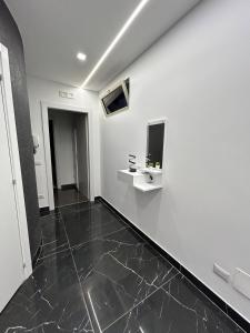 un corridoio con pareti bianche e pavimento piastrellato nero di Il piacere-Luxury apartments a Caltagirone
