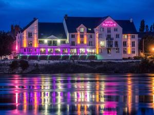 a building with lights on the water at night at Mercure Bords de Loire Saumur in Saumur