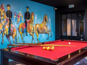 a pool table with cue balls and a painting of horses at Mercure Bords de Loire Saumur in Saumur