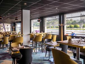 a dining room with tables and chairs and windows at Mercure Bords de Loire Saumur in Saumur