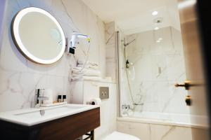 a bathroom with a sink and a mirror and a shower at Hôtel du Cheval Blanc - Paris Marne La Vallée in Jossigny
