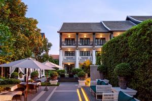 a building with tables and umbrellas in front of it at Siri Village Chiang Mai in Chiang Mai
