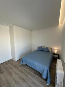Un dormitorio con una cama azul en una habitación blanca. en VAGUEIRA Sol, en Vagos