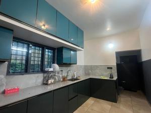 a large kitchen with blue cabinets and a sink at Misty cloud homestay in Pīrmed