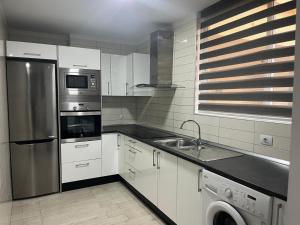 a kitchen with white cabinets and a stainless steel refrigerator at Green sea apartment in Adeje