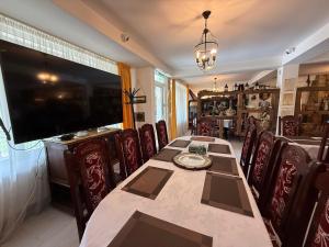 a dining room with a table and chairs and a television at Eisenau Luxury View in Prisaca Dornei