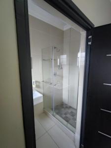 a glass shower in a bathroom with a toilet at 33onBazley Hotel in Durban