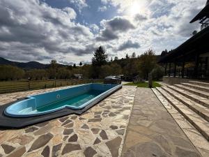 a swimming pool on a patio with a house at Eisenau Luxury View in Prisaca Dornei