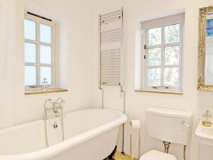 a white bathroom with a tub and a toilet at Courtyard Cottage, Pulborough in Pulborough +37 photos