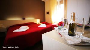 ein Hotelzimmer mit einem roten Bett und Weingläsern in der Unterkunft Rome Vatican Suite in Rom