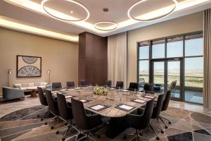 a conference room with a large table and chairs at Doubletree by Hilton Madinah Gate in Al ‘Awālī