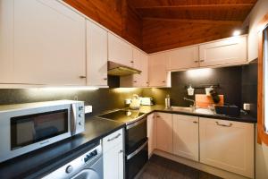 a kitchen with white cabinets and a microwave at Lyall Lodge in East Barcloy