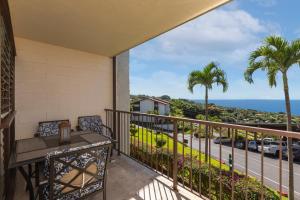 a balcony with a table and chairs and a view of the ocean at Kona Coffee Villas E246 condo in Honalo