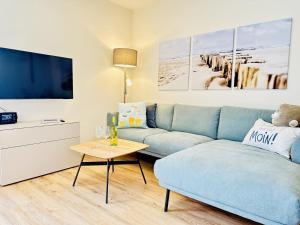 a living room with a blue couch and a tv at Küste33-22 Lotta in Tossenserdeich