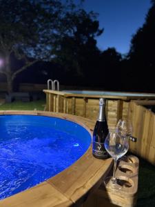 een fles wijn en glazen naast een hottub bij Gîte Domaine d'Hybère in Lucbardez-et-Bargues