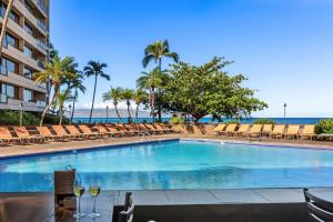a swimming pool with chairs and the ocean in the background at Oceanfront corner unit w/ ac! sk215- Sullivan in Kahana