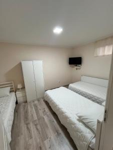 a bedroom with two beds and a tv on the wall at Prenociste-apartmani Laki S in Kula