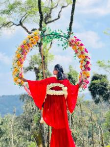 een vrouw in een rode jurk die een veld met bloemen vasthoudt bij Bee tree adventure park tent stay in Madikeri