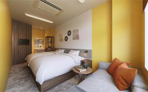 una habitación de hotel con una cama y un sofá en Red 28, en Ito