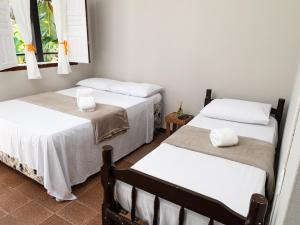 two beds in a room with white sheets and towels at Recanto D'Ajuda in Arraial d'Ajuda