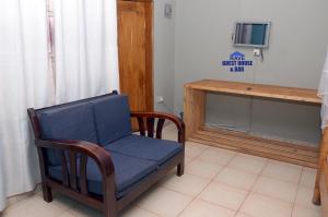 a living room with a blue chair and a tv at Rave Guest House and Bar in Mukono