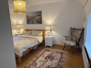 a bedroom with a bed and a chair and two lamps at Little Reds Seaview Cottage in Liscannor