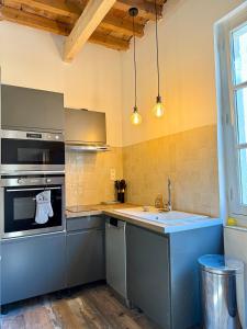 La cocina está equipada con fogones, fregadero y encimera. en Appartement Cosy avec balcon, en Arles
