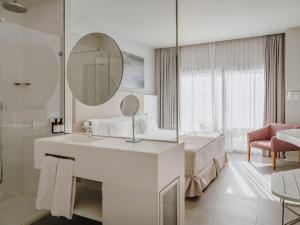 a white bathroom with a bed and a mirror at Grupotel Conil Playa in Cádiz +12 photos