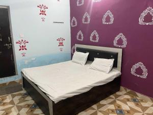 a bed in a room with a purple wall at Hotel O The Brothers Inn in Bāra Banki +7 photos