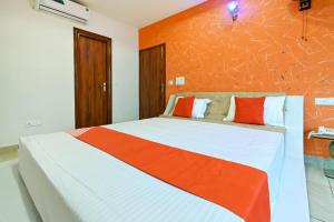 a bedroom with a bed with an orange wall at Collection O Royal King in Rohtak
