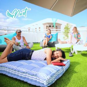 ラスパルマス・デ・グランカナリアにあるLas Palmas Nest Hostelの他の人々と一緒に芝生の上のベッドに横たわる女性
