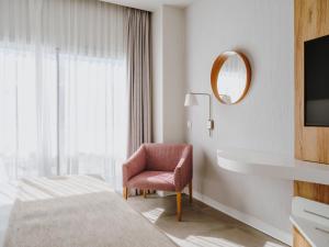 a bedroom with a bed and a chair and a mirror at Grupotel Conil Playa in Cádiz