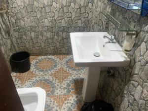 a bathroom with a sink and a stone wall at Martino Guest House in Pokuase