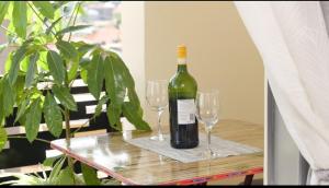 a bottle of wine and two wine glasses on a table at Cozy One Bedroom Apartment with Fast Fibre Wifi, Netflix, Hot Showers, Furnished Kitchen in Kampala