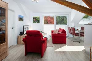 a living room with two red chairs and a table at Grashaus Groothusen in Krummhörn