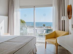a hotel room with a bed and a chair and a window at Grupotel Conil Playa in Cádiz