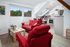 a living room with red furniture and a kitchen at Grashaus Groothusen in Krummhörn