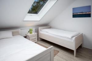 a attic bedroom with two beds and a window at Grashaus Groothusen in Krummhörn