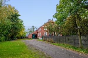 a dirt road in front of a red brick building at Grashaus Groothusen in Krummhörn